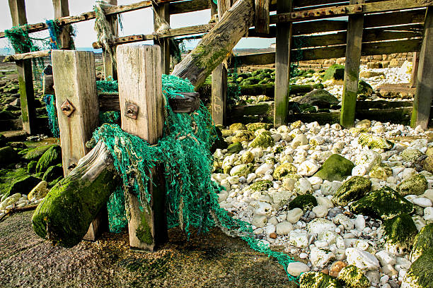 Old fishing nets stuck on sea groyne stock photo