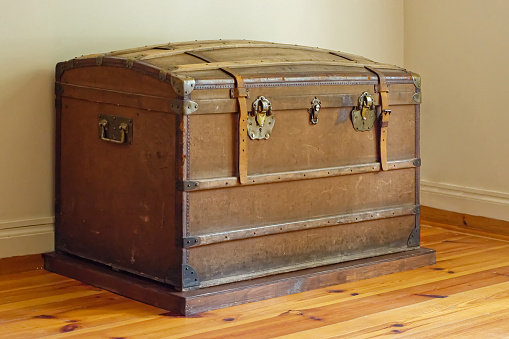 Old leather chest with iron brackets in the corner of the room.