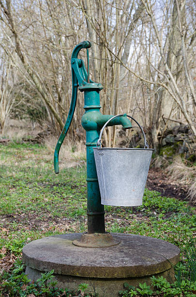 Old hand water pump with a bucket stock photo