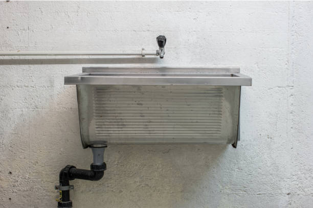 Old large metal wash sink and faucet wall mounted in a communal kitchen area