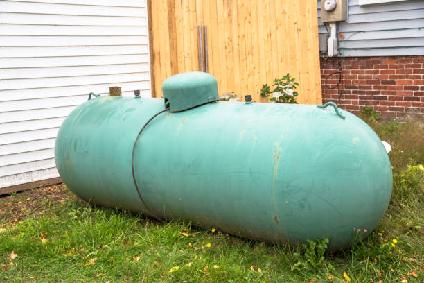 Old large propane tank in the backyard of a house Weathered large green propane tank in the backyard of a house. Wolfboro, NH, United States. gas tank stock pictures, royalty-free photos & images