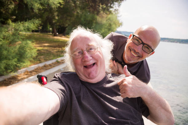 old man in wheelchair taking a selfie with his phone stock photo