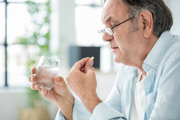 Old man taking a pill Old man taking a pill antibiotic photos stock pictures, royalty-free photos & images