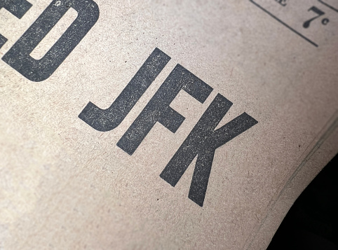 JFK old newsprint newspaper style headline font with selective focus tilt shift beige background.