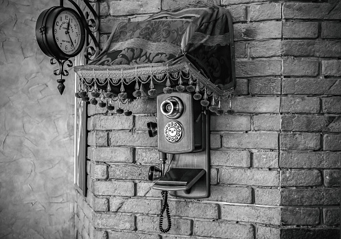 Old phone on the brick wall under the clock. decoration.
