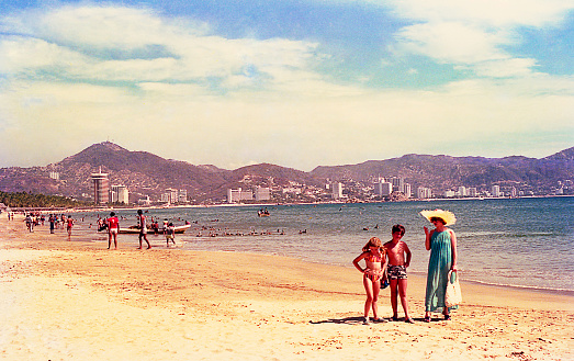 vintage saturated image of a mother and her children at the beach in Acapulco.