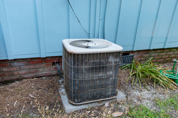 Old reusted air conditioner compresor sitting next to blue house stock photo