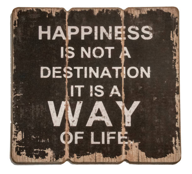 Old rustic wooden sign saying Happiness is not a destination it is a way of life - isolated on white. stock photo