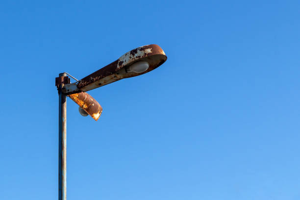 Old rusty street lamp in industrial style on a blue sky background stock photo