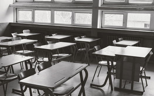 Old and abandoned school classroom interior, in black and white.