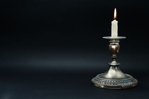 Old silver candle holder with lighted candle