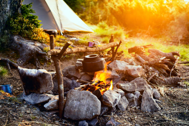 Old small kettle is heated on a bright bonfire stock photo