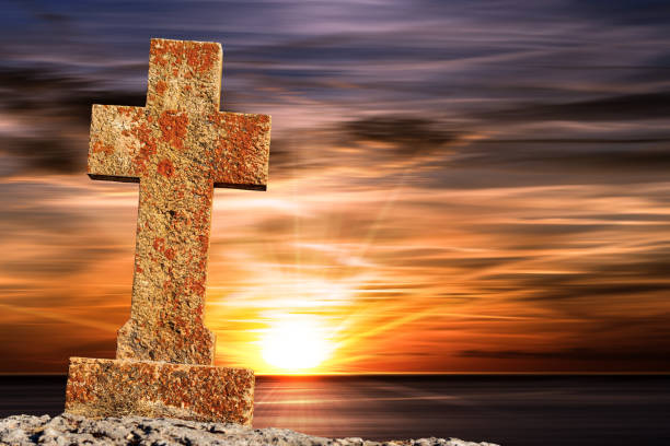 vieille croix religieuse en pierre contre un magnifique coucher de soleil sur la mer - good friday photos et images de collection