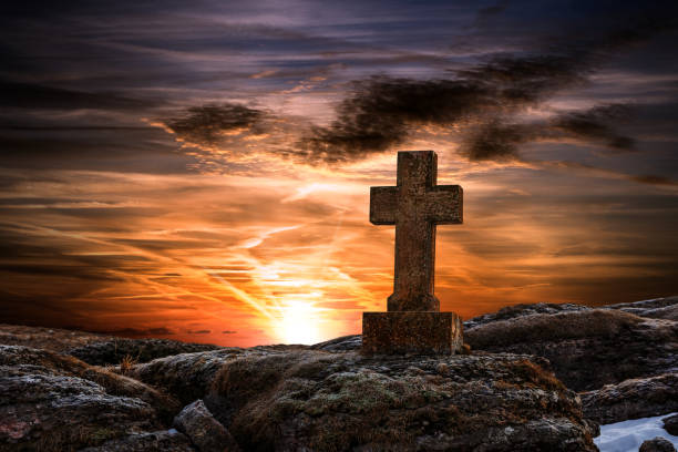 vieille croix religieuse en pierre sur un ciel sombre et dramatique au coucher du soleil - good friday photos et images de collection