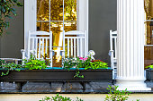 Old street historic Garden district in New Orleans, Louisiana with patio garden green plants flowers, white antebellum column and rocking chairs by mansion house