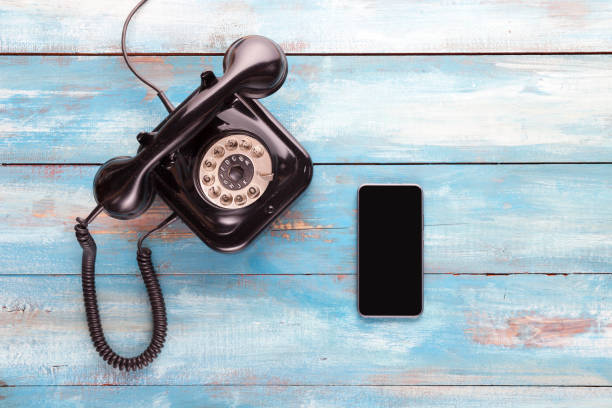 Old telephone and mobile phone on a blue wooden board stock photo