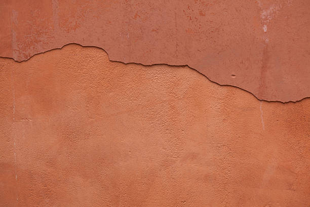 Old terracotta painted stucco wall with cracked plaster. Backgro stock photo