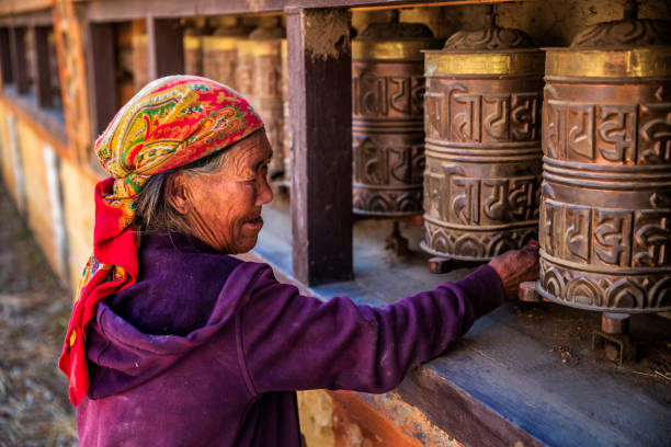 Old Tibetan woman turning the prayer wheels, Upper Mustang Old Tibetan woman turning the prayer wheels in a small village, Upper Mustang. Mustang region is the former Kingdom of Lo and now part of Nepal,  in the north-central part of that country, bordering the People's Republic of China on the Tibetan plateau between the Nepalese provinces of Dolpo and Manang. tibetan ethnicity stock pictures, royalty-free photos & images