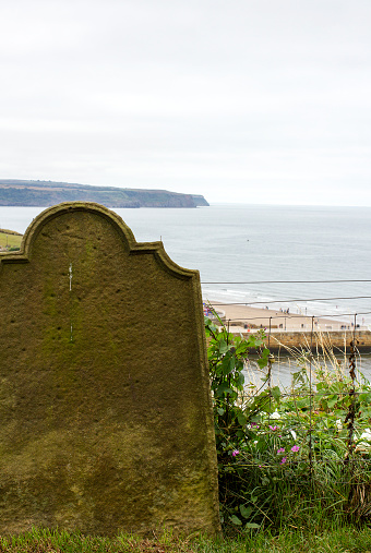 Colour photograph of an old Old tombstone overlooking the sea in Whitby England