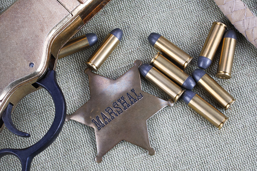 Old west rifle, ammunition and sheriff badge on canvas background