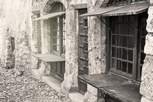 Horizontal composition sepia toned photography monochrome of old horizontal wooden shutter on old window from very ancient building with stone walls. This picture was taken in public streets of medieval village of Perouges in Ain, Rhone-Alpes region in France (Europe) without any people. It is from these ancient window shutters that comes the expression \