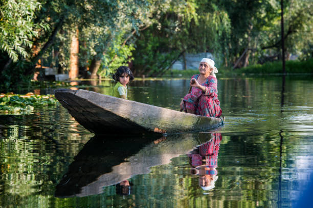 Old woman with girl in a boat, Lake Dal, India Srinagar, India - July 24, 2015: An elderly Kashmiri woman with a young girl in a shikara, a local wooden boat, on Lake Dal, Srinagar srinagar stock pictures, royalty-free photos & images