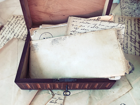 Vintage letters inside an old wooden box surrounded by more letters and documents