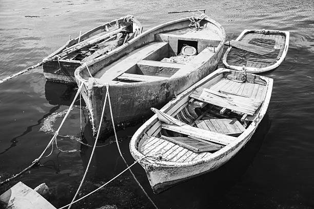 Old wooden fishing boats, black and white Old wooden fishing boats moored in small port of Avcilar, district of Istanbul, Turkey. Black and white retro stylized photo fishing industry photos stock pictures, royalty-free photos & images