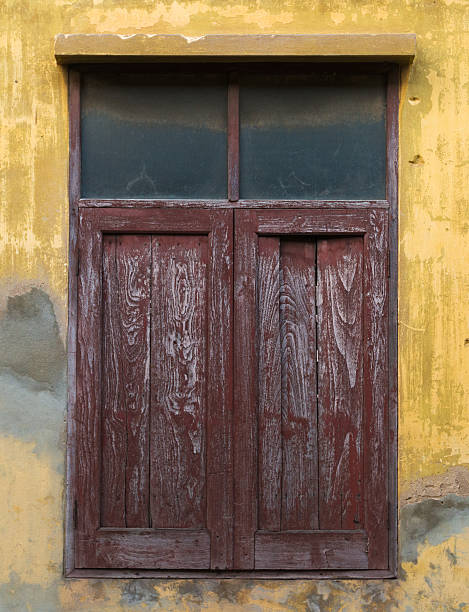Old wooden window on yellow weathered wall stock photo