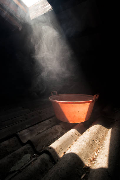 Old worn red bucket standing in a foggy environment on the attic. Red bucket lit by a ray of light from the attic window. stock photo