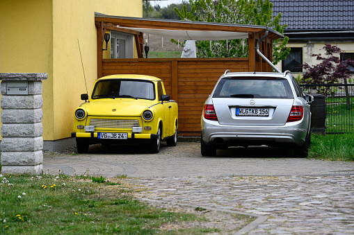 Pudagla, Germany, May 11, 2022 - Old yellow Trabant 601s car parked on a street side near a silver Mercedes Benz C-Class