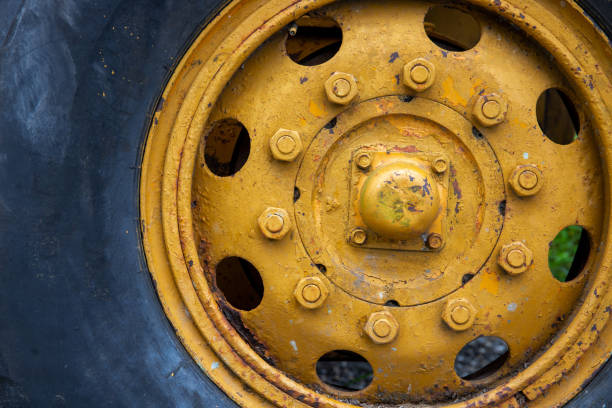 Old yellow wheel with black tire, rustic heavy machine detail photo. Working Tractor or grader detail. stock photo