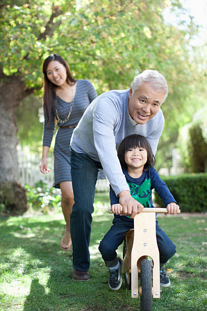 Older man pushing grandson in backyard  adult tricycle stock pictures, royalty-free photos & images