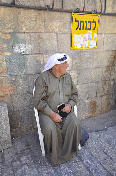 Older Muslim man sitting to his left holding the Quran stock photo