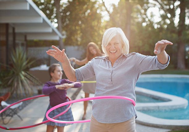 Older woman hula hooping in backyard  carefree stock pictures, royalty-free photos & images