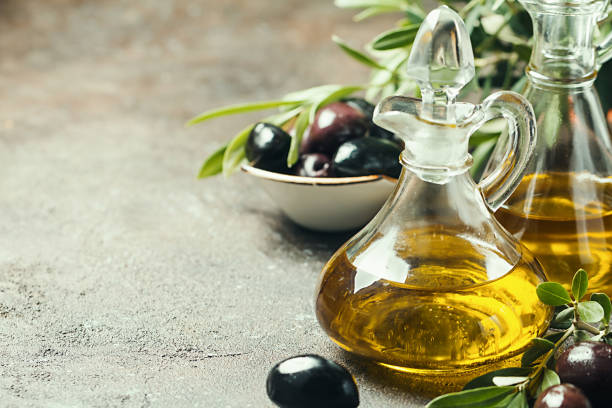 Olive oil and olive branch Olive oil in a glass bottle and olive branch on brown stone table olive oil stock pictures, royalty-free photos & images