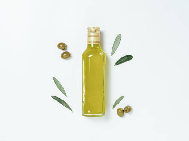 Olive oil glass bottle mock up, top view Olive oil glass bottle mock up. Top view of clear glass bottle with olive oil on white background with green olives and fresh green olive tree leaves. Copy space. olive oil stock pictures, royalty-free photos & images