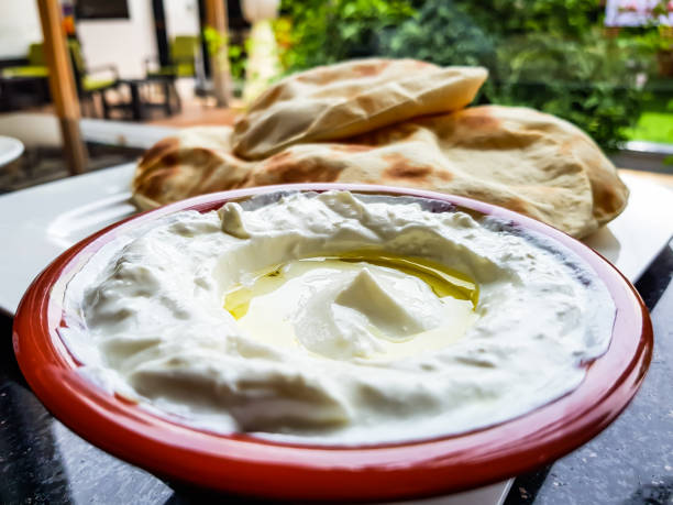 Olive oil in a bowl of labneh, a delicious traditional Arab yoghurt cream cheese dip, with freshly-baked flat bread in the background Close-up view of a middle-eastern dish of labneh and olive oil, with freshly-baked flat bread in the background. free jpeg images stock pictures, royalty-free photos & images