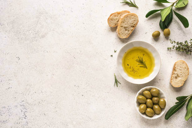 Olive Oil Organic Olive Oil in bowl with green olives, rosemary and ciabatta bread on white background ,top view, copy space. Healthy mediterranean food concept. olive fruit photos stock pictures, royalty-free photos & images