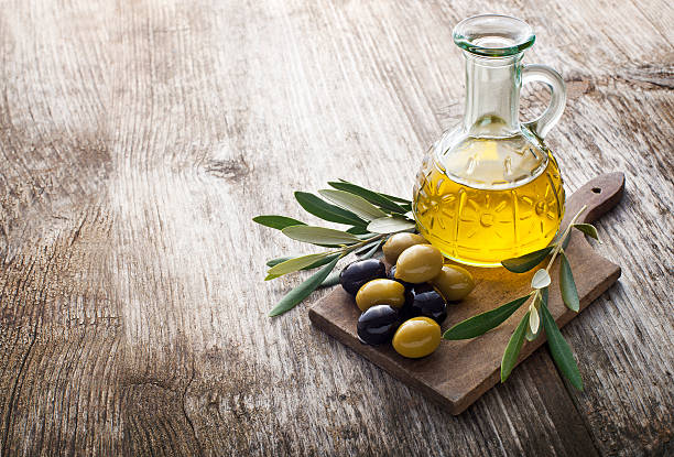 Olive oil Olive oil and olive branch on the wooden table olive oil stock pictures, royalty-free photos & images