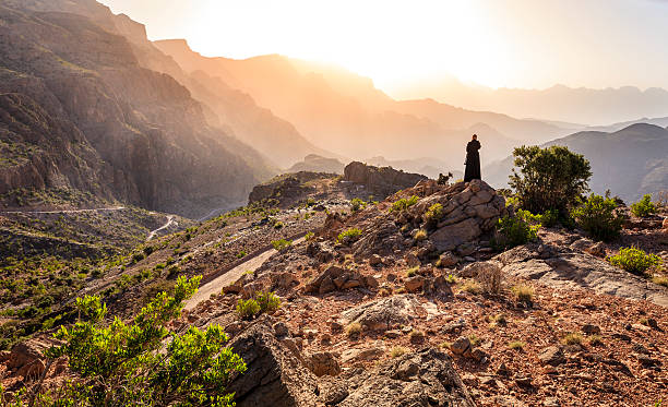 Omani woman in the mountains Lone woman in abaya in Al Hajar Mountains of Oman at sunset oman stock pictures, royalty-free photos & images