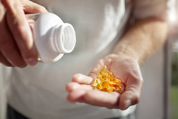 Omega 3 fish oil capsules Bottle of omega 3 fish oil capsules pouring into hand fish oil stock pictures, royalty-free photos & images