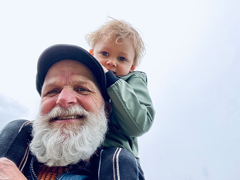 Toddler boy making a trip on granddad shoulder