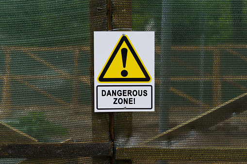 Security concept. On the fence hangs a warning sign and a sign with the inscription - Dangerous zone