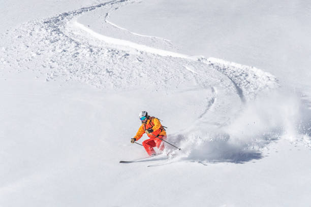 One adult freeride skier skiing downhill through deep powder snow one man skiing, white snowy background, deep powder snow powder mountain stock pictures, royalty-free photos & images