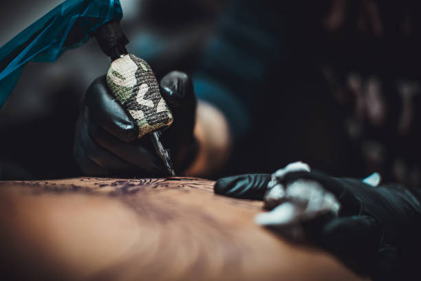 One artist tattooing a man's back in studio stock photo