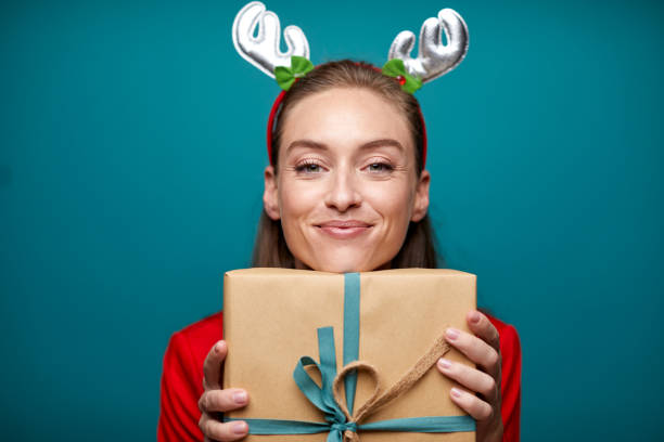one beautiful woman proudly holding a christmas gift. - woman holding a christmas gift imagens e fotografias de stock