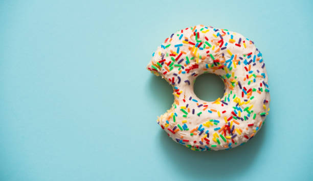 One bite missing of donut on blue background One bite missing of donut on blue background. doughnut stock pictures, royalty-free photos & images