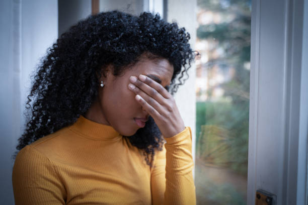 One black woman depressed in front of window stock photo