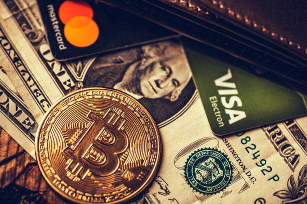 One coin of bitcoin on a black brown with dollars and the cards Visa , Mastercard stock photo